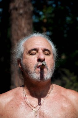 handsome senior man smoking cuban cigar enjoying summer vacation and suntan on retirement.