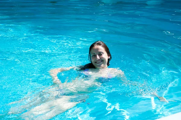 cheerful woman swimming in summer pool water on vacation.