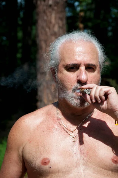 aged man smoking cuban cigar enjoying summer vacation and suntan on retirement.