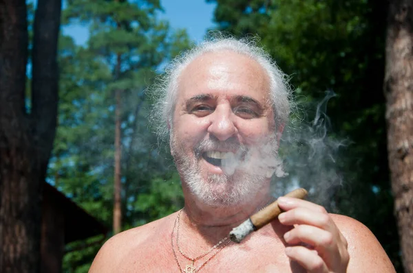 glad senior man smoking cuban cigar enjoying summer vacation and suntan on retirement.