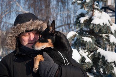 İnsan kışın evcil hayvanla oynar. Evcil hayvan sever bir adam köpeğiyle oynuyor. Dışarıda evcil hayvanlı bir adam. İnsanlarla açık havada oynaşan.