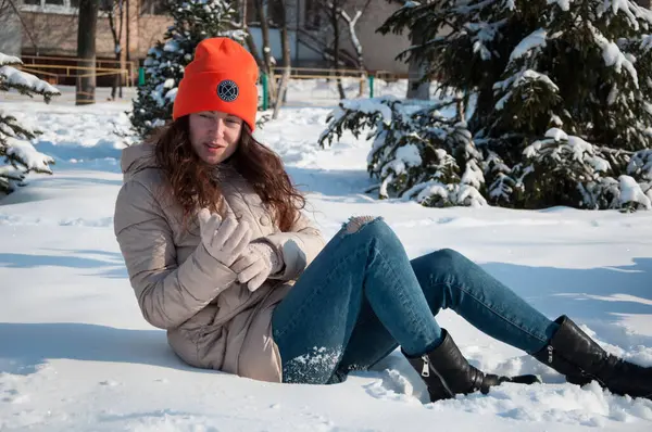 Sıcak şapkalı kış kadını kışın kar altında oturur. Kış mevsiminde kar yağan kalın şapkalı kadın modası..