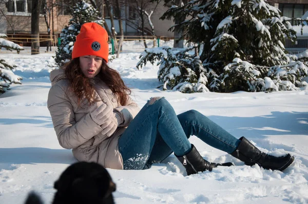 冬日的女人戴着橙色的暖和的帽子坐在雪地里过冬 冬雪中戴着温暖帽子的女人的冬季风尚 — 图库照片