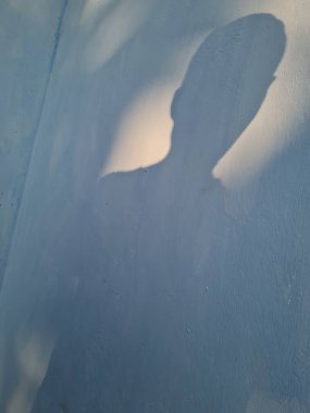 Duvardaki erkek gölgesinin soyut arkaplanı mavi renkli.