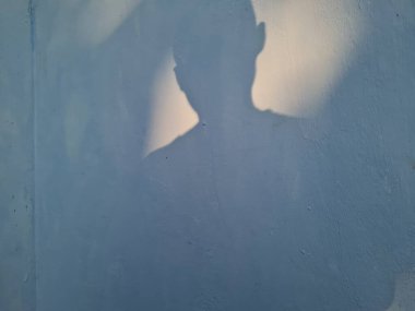 Duvardaki erkek gölgesinin soyut arkaplanı mavi renkli.