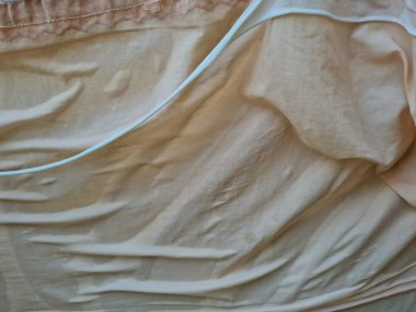 Açık kahverengi kumaş arka plan güneşte katlanmış.