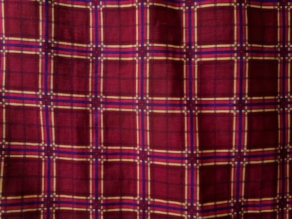 Soyut arkaplan fotoğrafı sarı kareli çizgilerin kombinasyonlu kırmızı bir sarong tasvir ediyor.