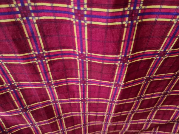 Soyut arkaplan fotoğrafı sarı kareli çizgilerin kombinasyonlu kırmızı bir sarong tasvir ediyor.