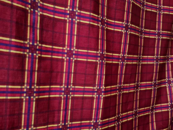 Soyut arkaplan fotoğrafı sarı kareli çizgilerin kombinasyonlu kırmızı bir sarong tasvir ediyor.