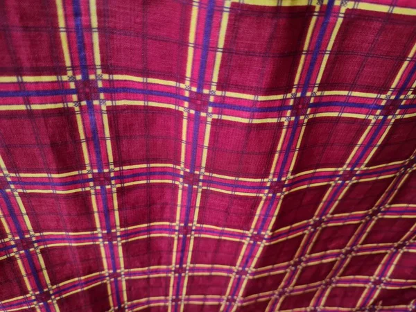 Soyut arkaplan fotoğrafı sarı kareli çizgilerin kombinasyonlu kırmızı bir sarong tasvir ediyor.