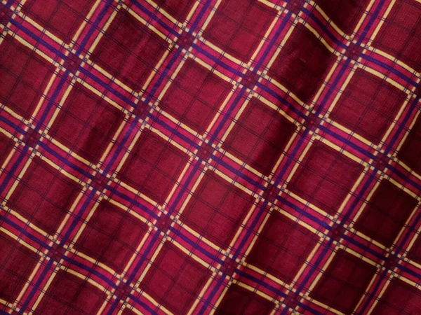 Soyut arkaplan fotoğrafı sarı kareli çizgilerin kombinasyonlu kırmızı bir sarong tasvir ediyor.