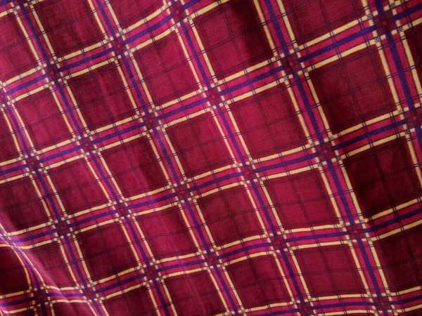 Soyut arkaplan fotoğrafı sarı kareli çizgilerin kombinasyonlu kırmızı bir sarong tasvir ediyor.