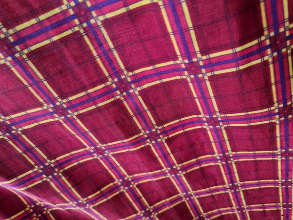 Soyut arkaplan fotoğrafı sarı kareli çizgilerin kombinasyonlu kırmızı bir sarong tasvir ediyor.