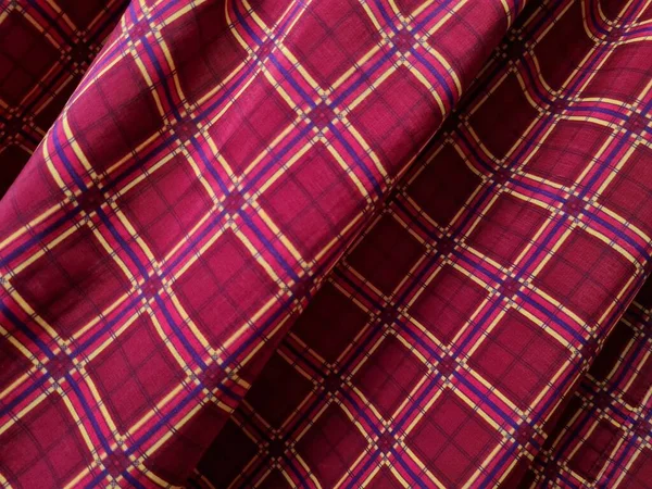 Soyut arkaplan fotoğrafı sarı kareli çizgilerin kombinasyonlu kırmızı bir sarong tasvir ediyor.