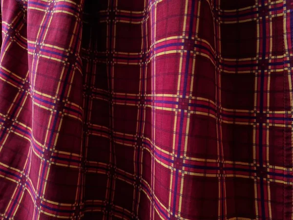 Soyut arkaplan fotoğrafı sarı kareli çizgilerin kombinasyonlu kırmızı bir sarong tasvir ediyor.