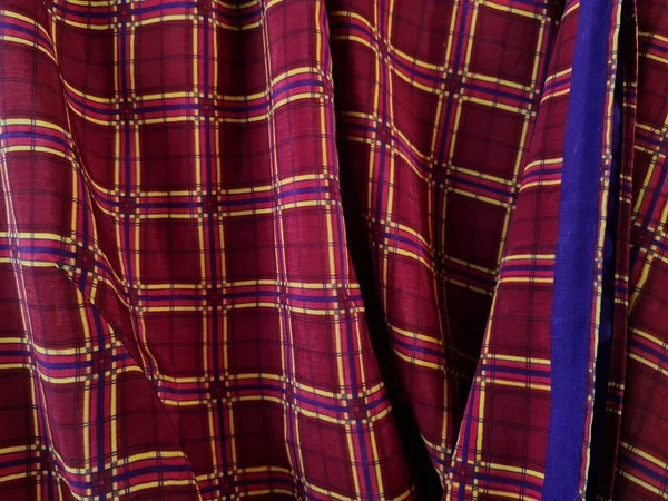 Soyut arkaplan fotoğrafı sarı kareli çizgilerin kombinasyonlu kırmızı bir sarong tasvir ediyor.