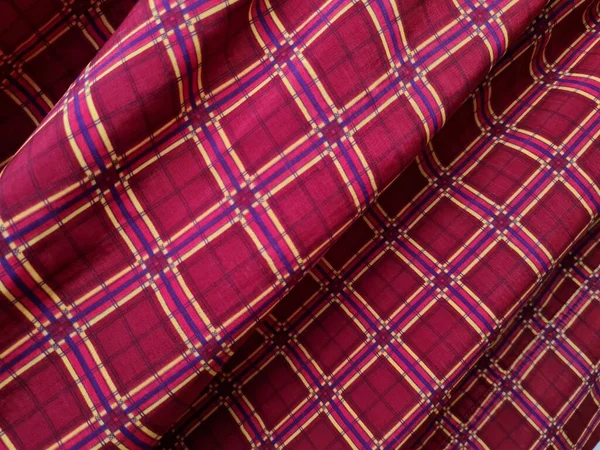 Soyut arkaplan fotoğrafı sarı kareli çizgilerin kombinasyonlu kırmızı bir sarong tasvir ediyor.