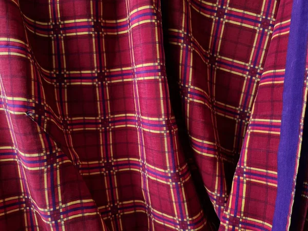 Soyut arkaplan fotoğrafı sarı kareli çizgilerin kombinasyonlu kırmızı bir sarong tasvir ediyor.