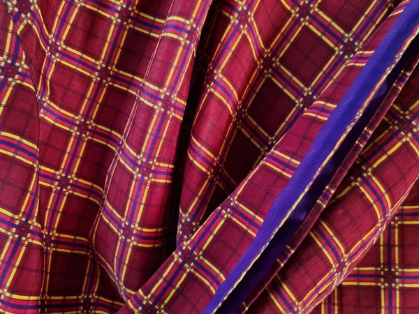 Soyut arkaplan fotoğrafı sarı kareli çizgilerin kombinasyonlu kırmızı bir sarong tasvir ediyor.