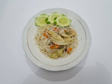 Pişmiş beyaz vermicelli artı dilimlenmiş havuç, hardal yeşili, üzerinde beyaz bir tabakta dilimlenmiş salatalık.