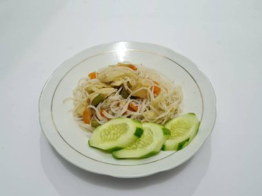 Pişmiş beyaz vermicelli artı dilimlenmiş havuç, hardal yeşili, üzerinde beyaz bir tabakta dilimlenmiş salatalık.