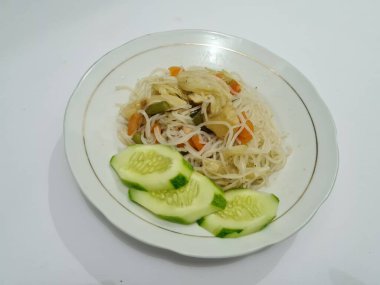 Pişmiş beyaz vermicelli artı dilimlenmiş havuç, hardal yeşili, üzerinde beyaz bir tabakta dilimlenmiş salatalık.