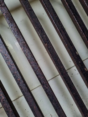 Önündeki beyaz ahşap kapının arka planı güvenlik olarak kahverengi bir demir çit.