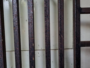 Önündeki beyaz ahşap kapının arka planı güvenlik olarak kahverengi bir demir çit.