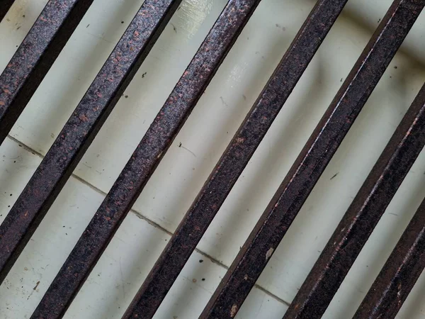 Önündeki beyaz ahşap kapının arka planı güvenlik olarak kahverengi bir demir çit.