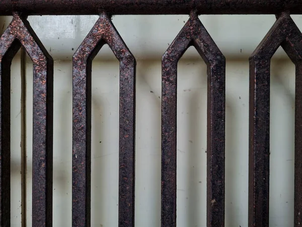 Önündeki beyaz ahşap kapının arka planı güvenlik olarak kahverengi bir demir çit.