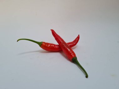 Beyaz arka planda yeşil saplı büyük kırmızı biber, bu kırmızı biber genellikle yemek pişirmek için kullanılan malzemelerden biridir.