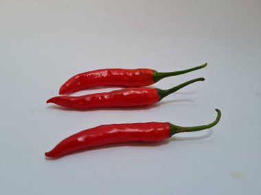 Beyaz arka planda yeşil saplı büyük kırmızı biber, bu kırmızı biber genellikle yemek pişirmek için kullanılan malzemelerden biridir.