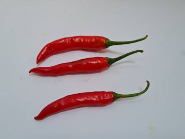 Beyaz arka planda yeşil saplı büyük kırmızı biber, bu kırmızı biber genellikle yemek pişirmek için kullanılan malzemelerden biridir.