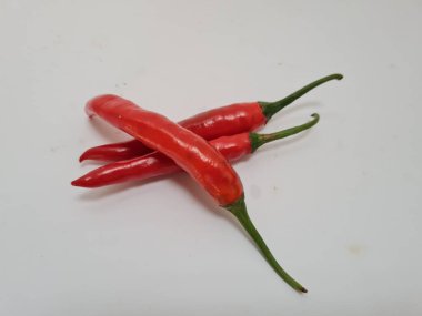Beyaz arka planda yeşil saplı büyük kırmızı biber, bu kırmızı biber genellikle yemek pişirmek için kullanılan malzemelerden biridir.