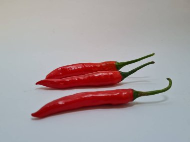 Beyaz arka planda yeşil saplı büyük kırmızı biber, bu kırmızı biber genellikle yemek pişirmek için kullanılan malzemelerden biridir.