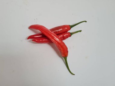 Beyaz arka planda yeşil saplı büyük kırmızı biber, bu kırmızı biber genellikle yemek pişirmek için kullanılan malzemelerden biridir.