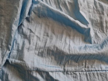 Parlak açık mavi kumaşlı, düzensiz kırışıklıkları ve gölgeleri olan soyut arkaplan kombinasyonu