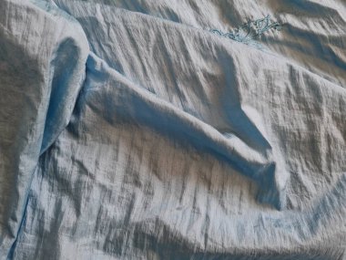 Parlak açık mavi kumaşlı, düzensiz kırışıklıkları ve gölgeleri olan soyut arkaplan kombinasyonu