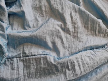 Parlak açık mavi kumaşlı, düzensiz kırışıklıkları ve gölgeleri olan soyut arkaplan kombinasyonu