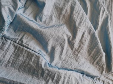 Parlak açık mavi kumaşlı, düzensiz kırışıklıkları ve gölgeleri olan soyut arkaplan kombinasyonu