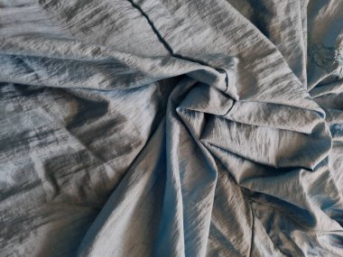 Abstract background textured with shiny light blue fabric with irregular creases and shadows as a combination