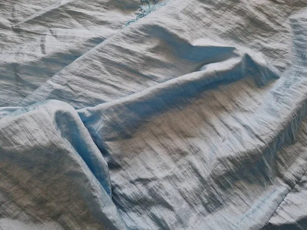 Parlak açık mavi kumaşlı, düzensiz kırışıklıkları ve gölgeleri olan soyut arkaplan kombinasyonu