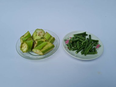 Yeşil patlıcan dilimleri ve yeşil fasulyeler beyaz ve mavi kombinasyonlarda izole edilmiş.