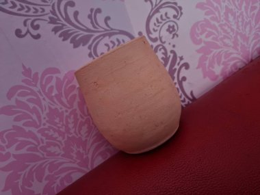 Duvarında pembe bir süs olan kahverengi topraktan yapılmış bir sürahi.