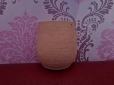 Duvarında pembe bir süs olan kahverengi topraktan yapılmış bir sürahi.