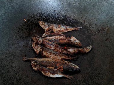 Altı baharatlı bir tavada kızarmış deniz balığı.