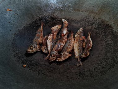 Altı baharatlı bir tavada kızarmış deniz balığı.