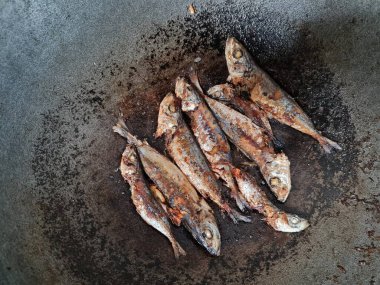 Altı baharatlı bir tavada kızarmış deniz balığı.
