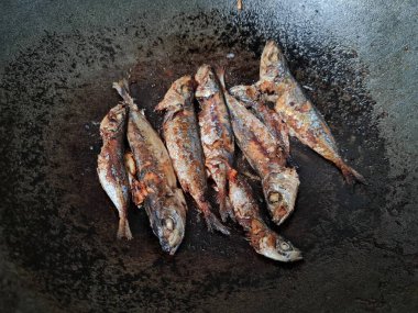 Altı baharatlı bir tavada kızarmış deniz balığı.