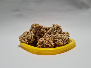 Rengginang denilen hafif bir atıştırmalık un ve sarı bir kabın içindeki diğer koyu kahverengi malzemelerden yapılır.